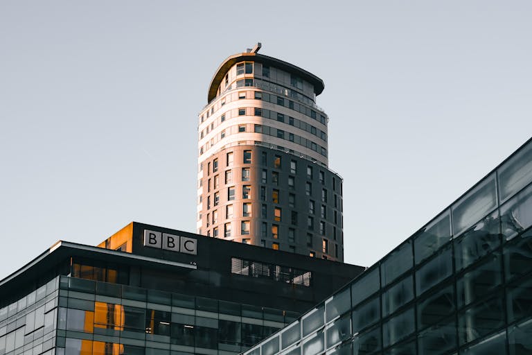 Modern architecture of the BBC building at Salford Quays, highlighted by warm sunlight during the golden hour.
