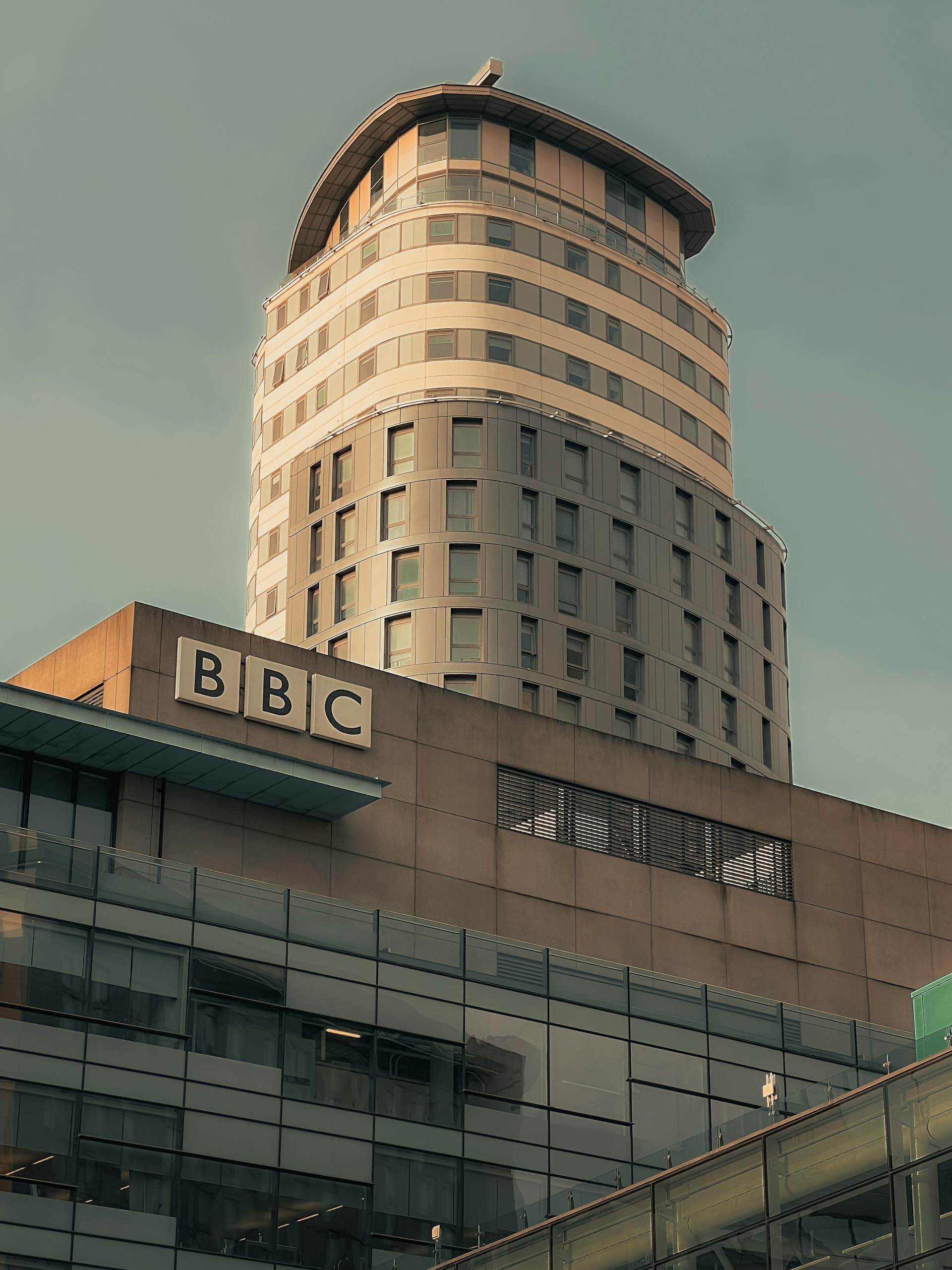 Glass and concrete architecture of BBC skyscraper in Manchester under a clear sky.